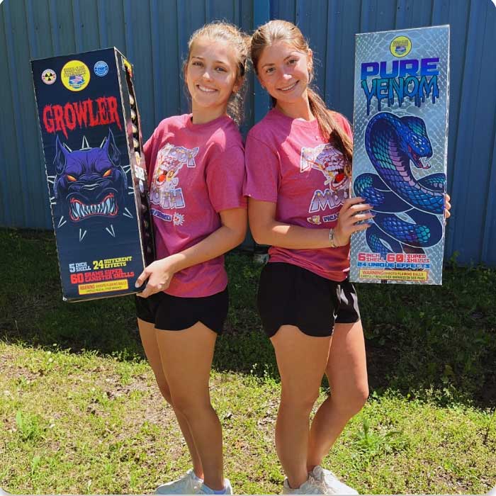 Refer A Friend - two young woman standing back to back holding large fireworks boxes